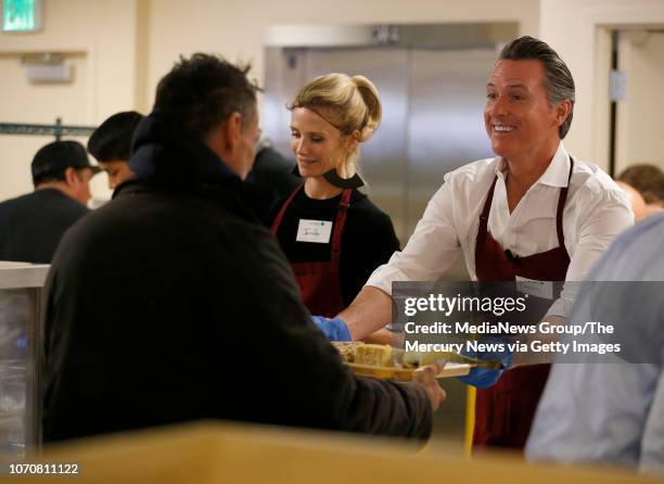 Governor-elect Gavin Newsom and his wife Jennifer, left, hand out free meals at the St. Anthony Foundation's dining room in San Francisco, Calif., on...