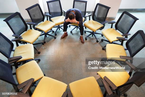 a man hanging his head down in the circle of chairs - internal communication stock pictures, royalty-free photos & images