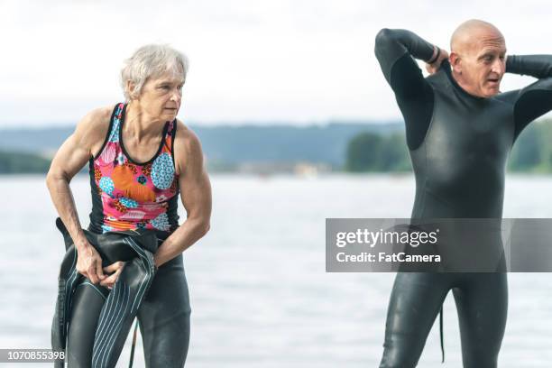 two senior triathletes preparing for swim stage - triathlon stock pictures, royalty-free photos & images