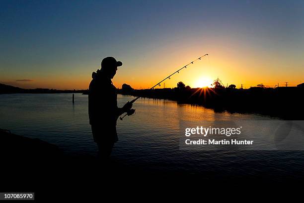 Young man fishes at sunset on the Grey River on November 23, 2010 in Greymouth, New Zealand. Leading figures in the community and rescue team...