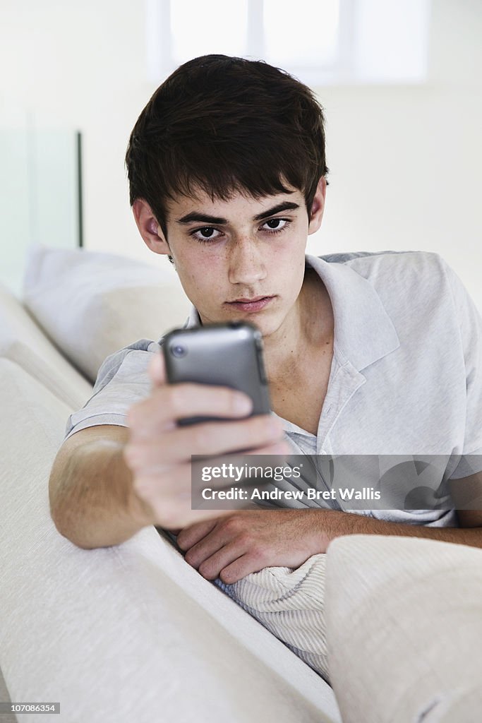 Male youth using a mobile phone in the home