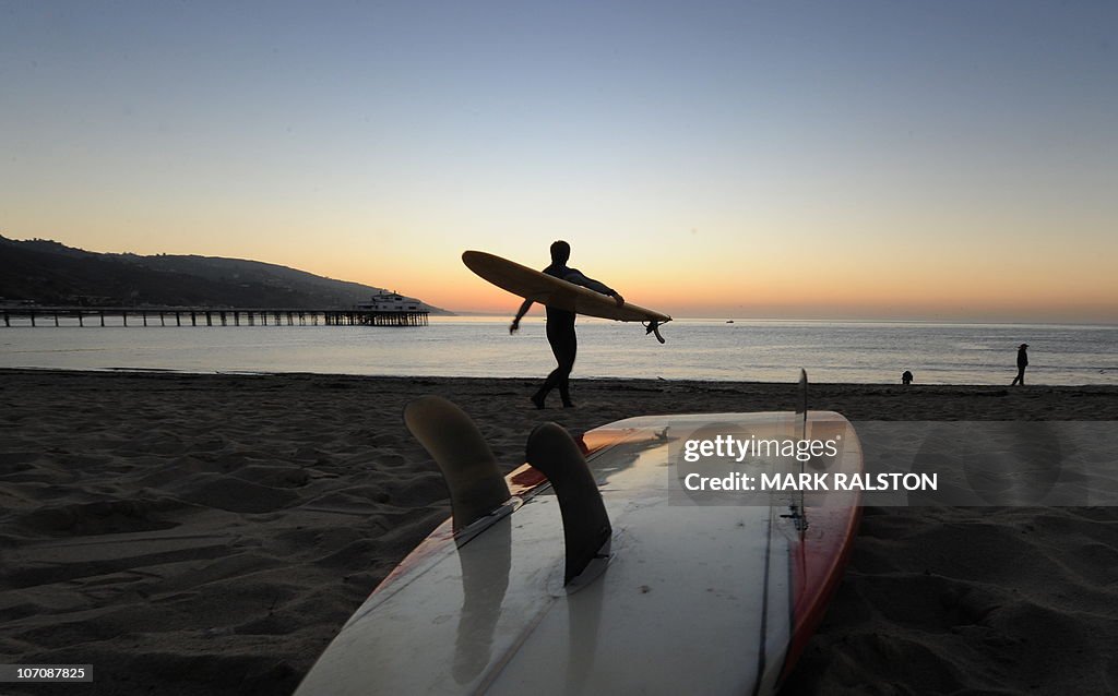 A surfer enters the water before tribal