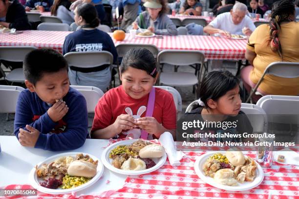 Hessler Gomez sits with sisters Genesis Perez and Aylin Gomez while they eat a turkey dinner during the Hope of the Valley Rescue Mission 10th Annual...