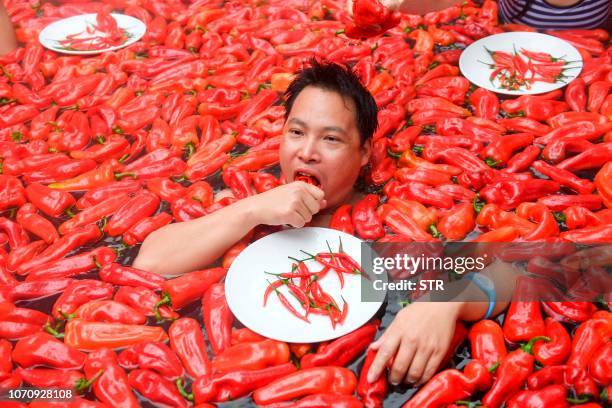 This photo taken on December 9, 2018 shows a competitor taking part in a chilli pepper eating contest in a hot spring filled with chilli peppers in...