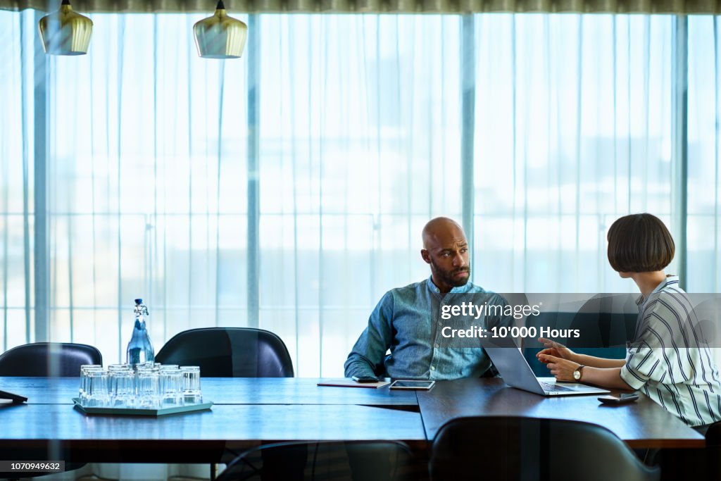 Female manager talking to male colleague in board room