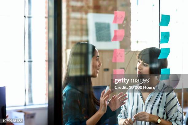 candid portrait of chinese businesswoman talking to female colleague - thinking outside the box englische redewendung stock-fotos und bilder