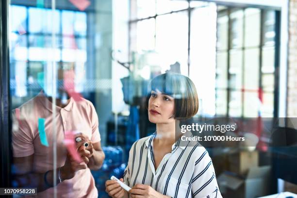 businesswoman looking at sticky notes with curious expression - new business growth stock pictures, royalty-free photos & images