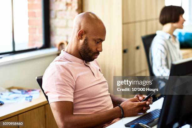 portrait of serious businessman using smart phone at desk - perder el tiempo fotografías e imágenes de stock