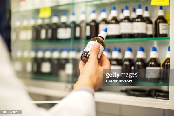 apotheker mit einer medizin-flasche in der hand - homöopathie stock-fotos und bilder