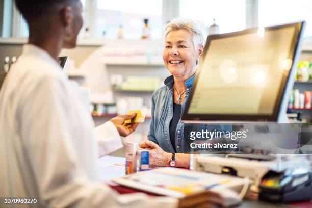 chemist giving the card to costumer after the payment - paying doctor stock pictures, royalty-free photos & images