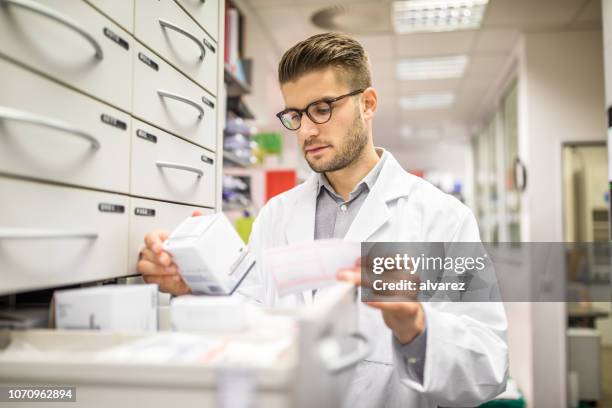 pharmacist checking medicines on rack - pharmacy stock pictures, royalty-free photos & images