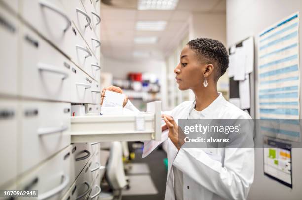 mujer farmacéutico en busca de medicinas en el rack - material médico fotografías e imágenes de stock
