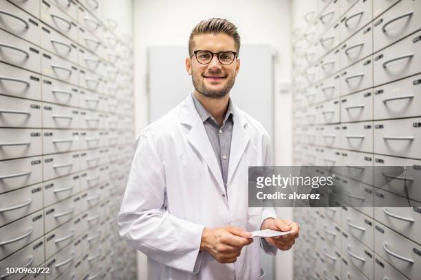 farmacista con prescrizione medica in ripostiglio - pharmacist foto e immagini stock