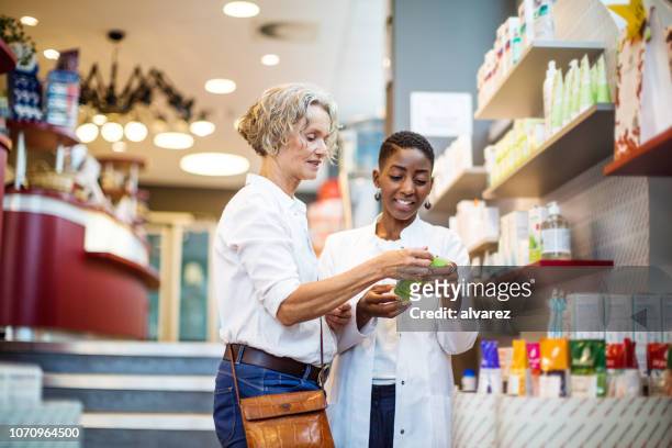 female pharmacist assisting senior customer - pharmacist explaining stock pictures, royalty-free photos & images