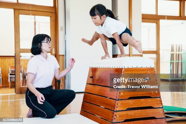 young girl practicing gymnastics at preschool in japan - gymnastic asian stockfoto's en -beelden