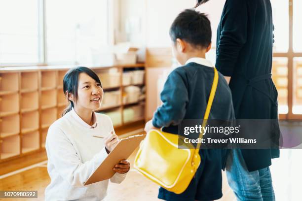 mother dropping off young son at preschool - child care worker stockfoto's en -beelden