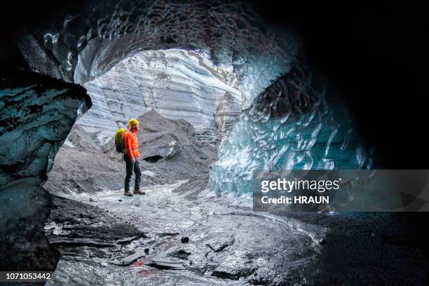 hiker exploring ice cave at glacier. - myrdalsjokull glacier stock pictures, royalty-free photos & images