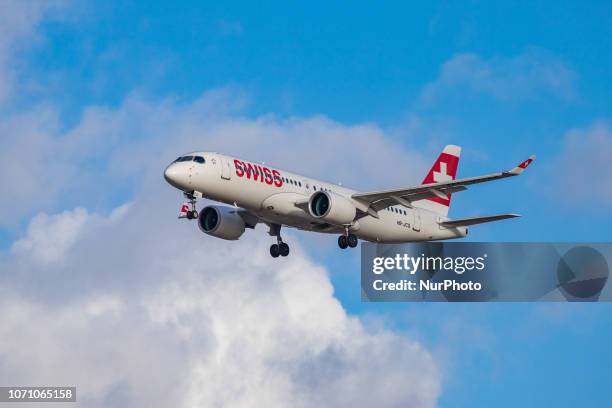 Swiss Airbus A220-300 aircraft with registration HB-JCQ landing at London Heathrow Airport in England, UK in the blue sky. The Airbus A220 is a new...