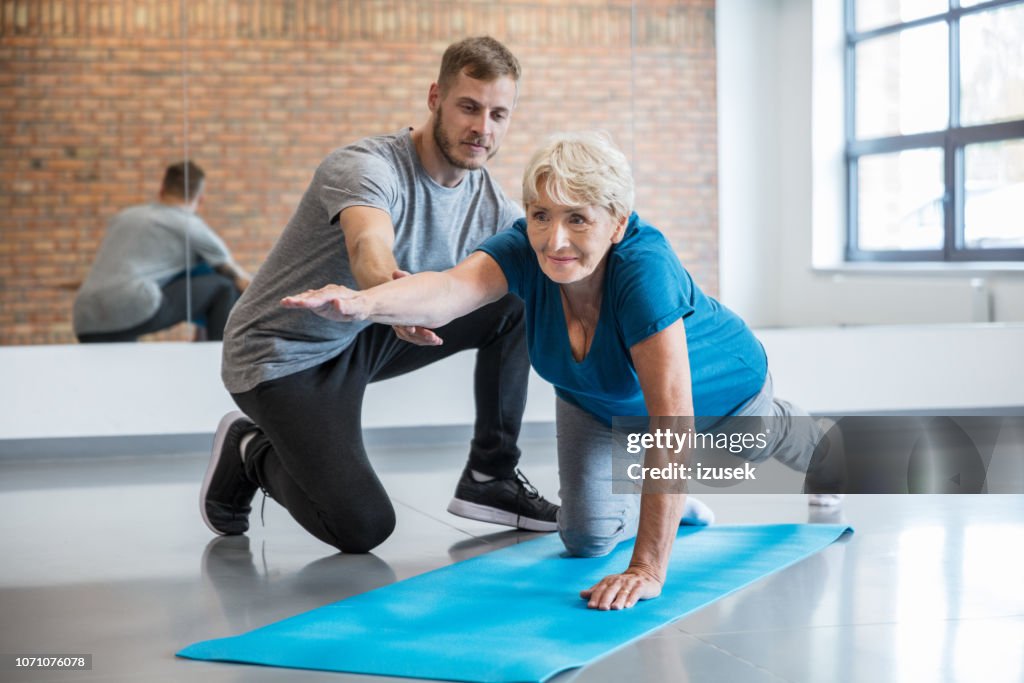 Senior mujer haciendo ejercicio con entrenador en rehab