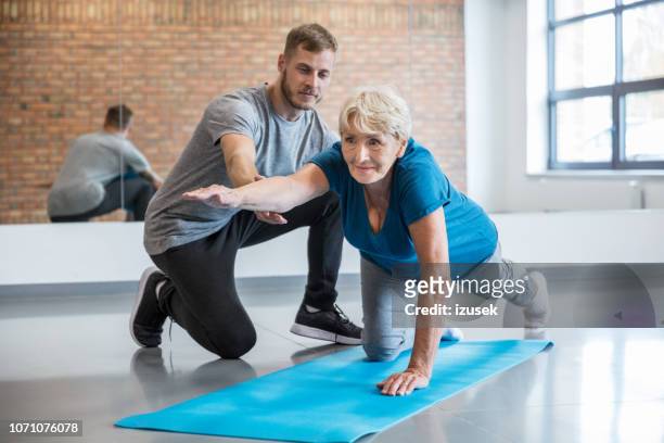 senior mujer haciendo ejercicio con entrenador en rehab - fitness instructor fotografías e imágenes de stock