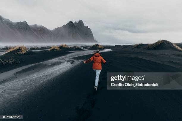 Woman running away near  Vestrahorn mountains near the sea