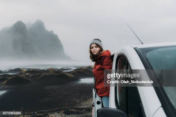 Woman looking from car near  Vestrahorn mountains near the sea