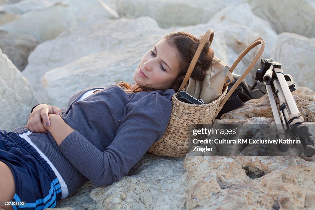 Woman reclining on rocky beach