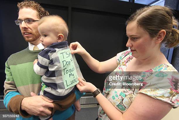 Caleb Christian, left, holds Keaton Lyons as his mother Michelle Lyons tapes a sign on Keaton that says "TSA Don't touch my Lunch" as part of a...