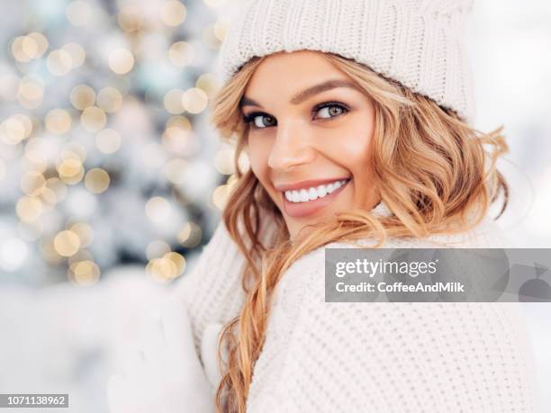 schöne mädchen sitzen in der nähe von neujahr baum - face snow stock-fotos und bilder