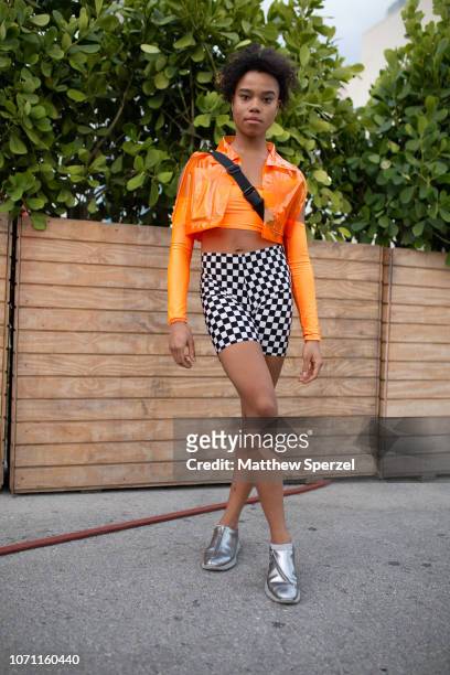 Guest is seen on the street in Wynwood during Miami Art Week wearing orange plastic jacket with spandex orange shirt and checker shorts on December...