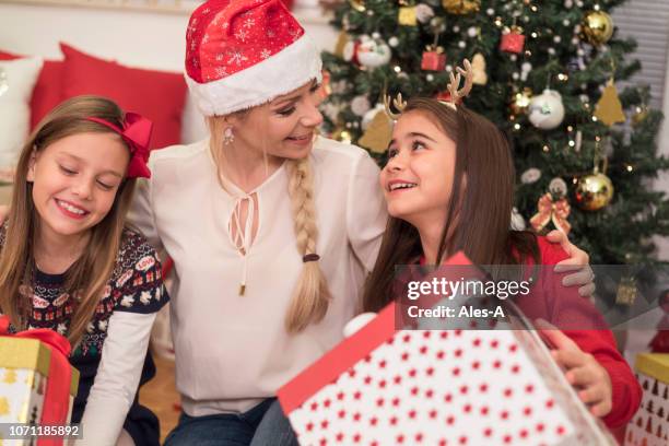 cute little girls with their mother on christmas - christmas presents under tree stock pictures, royalty-free photos & images