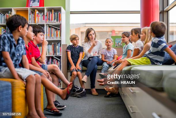 teacher teaching multi-ethnic students in library - teacher taking attendance stock pictures, royalty-free photos & images