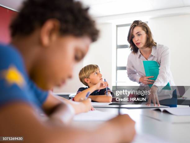 young teacher helping students in classroom - teacher with folder stock pictures, royalty-free photos & images