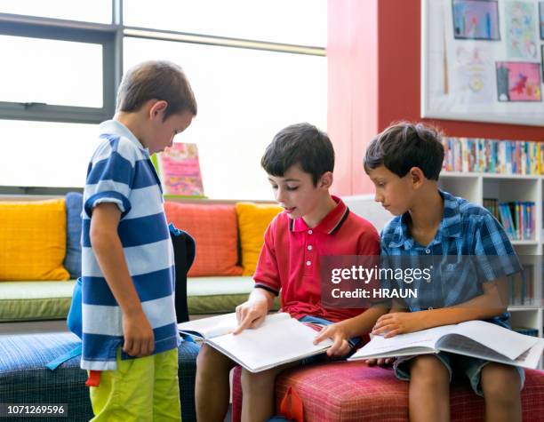 schoolboy reading to classmates in library - boy library stock pictures, royalty-free photos & images