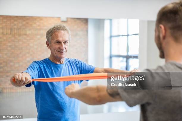 senior man exercising with resistance band at rehab - drug rehab stock pictures, royalty-free photos & images