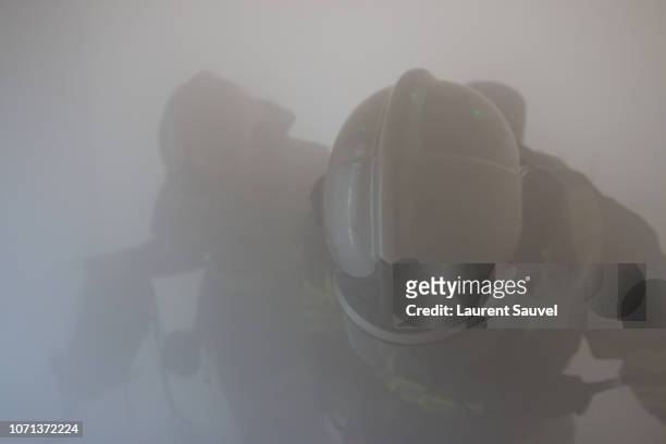 two firefighters at work hidden by smoke - laurent sauvel photos et images de collection