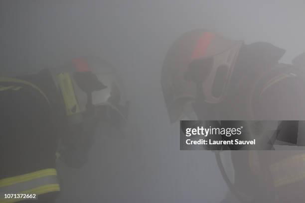 two firefighters at work hidden by smoke - laurent sauvel photos et images de collection