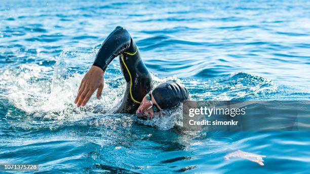 open water zwemmer zwemmen in zee - triatlon stockfoto's en -beelden