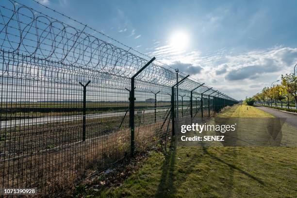 view of border separated by barbed wire against clear sky - prison escape stock pictures, royalty-free photos & images