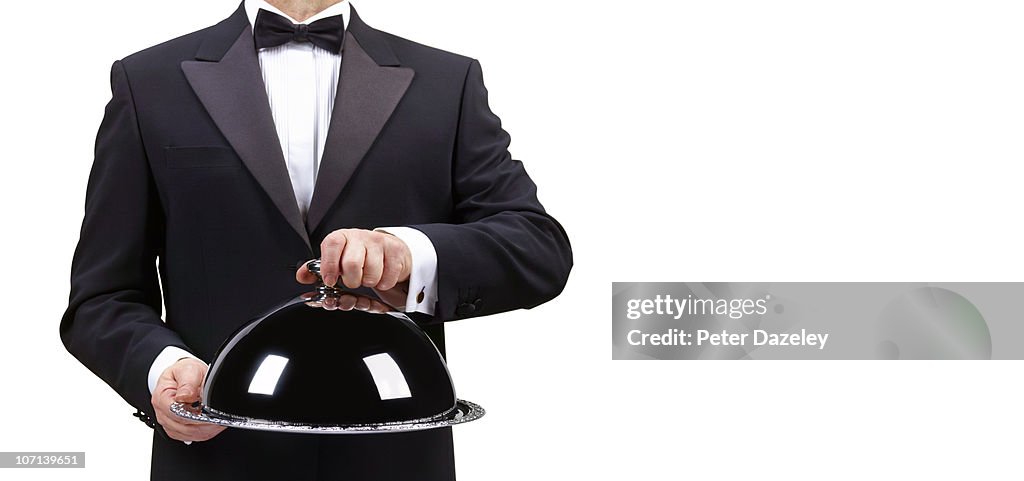 Butler presenting domed dish with copy space