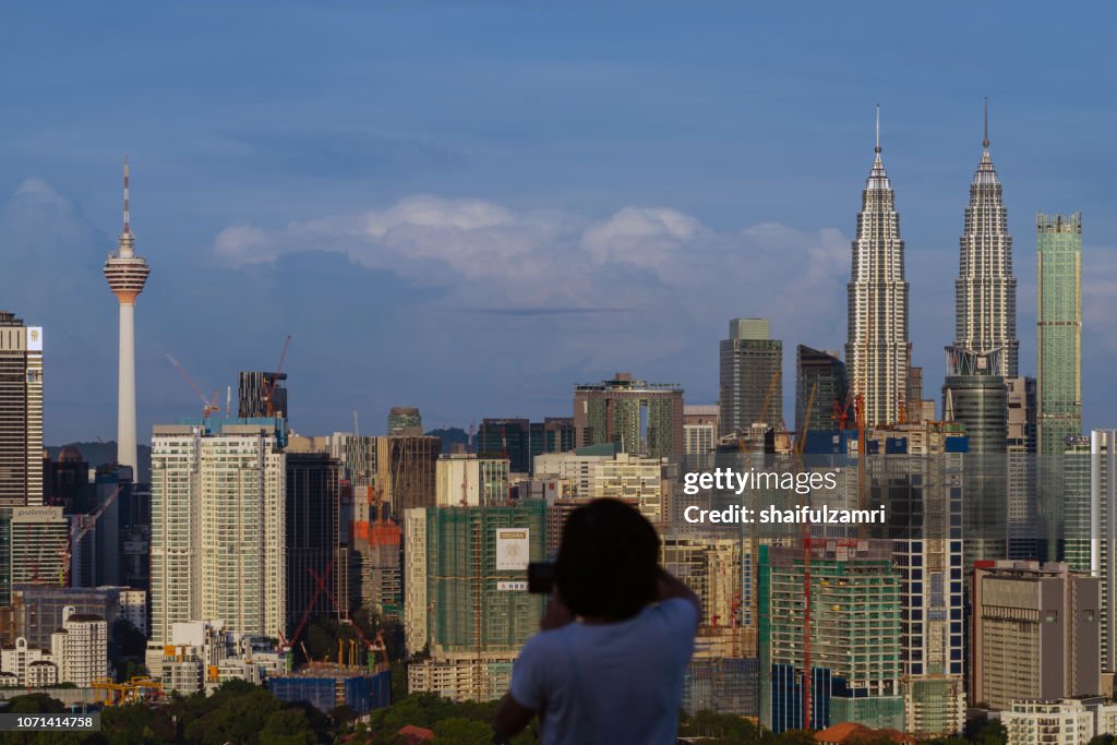 Unidentified tourist shots a picture of morning light over downtown Kuala Lumpur, Malaysia.