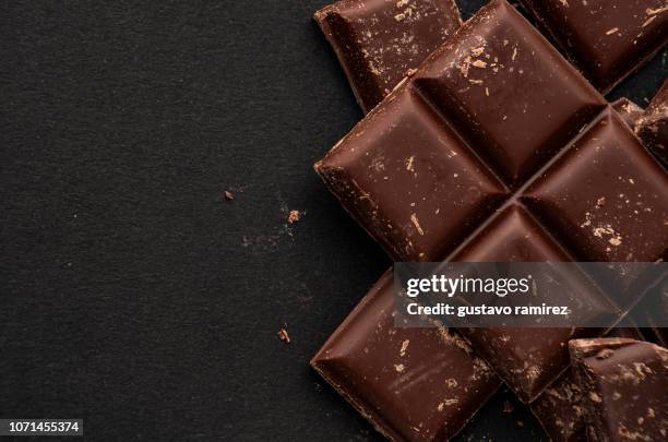 pieces of dark chocolate on black background - chocolate bean stock pictures, royalty-free photos & images