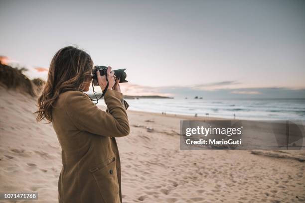 junge frau, die eine aufnahme mit einer modernen dslr-kamera - professional photographer stock-fotos und bilder