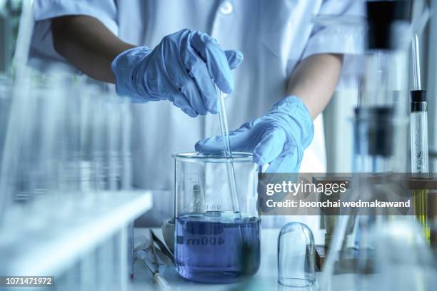 lab worker putting medical blood sample in place after examining for sediments - reagente - fotografias e filmes do acervo