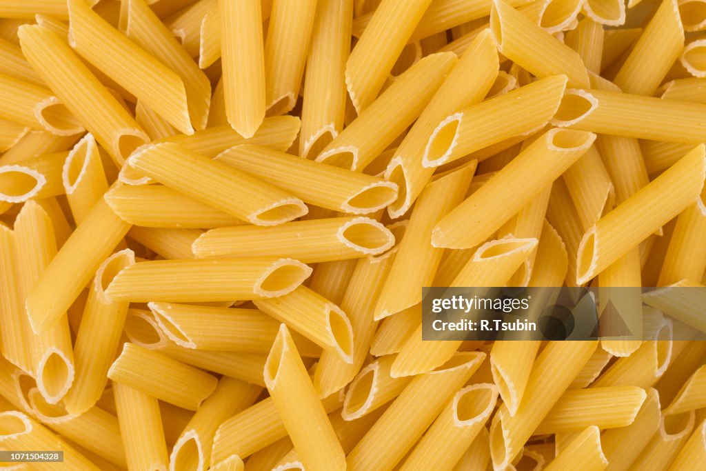 Closeup photo of uncooked italian penne pasta background