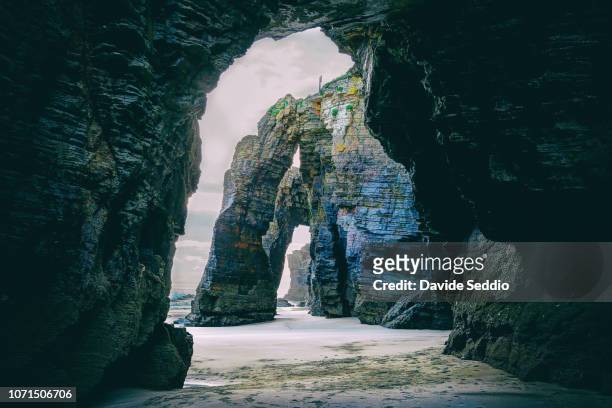 natural arches during sunset on the beach of the cathedrals on the north galician coastline - galizien stock-fotos und bilder