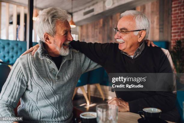 lachende oude mannen die knuffelen - alleen seniore mannen stockfoto's en -beelden