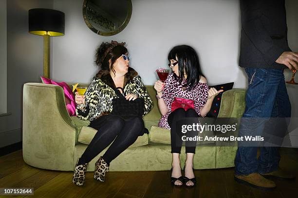 females on a sofa at a party fancy a male guest - bizarre fashion stock pictures, royalty-free photos & images