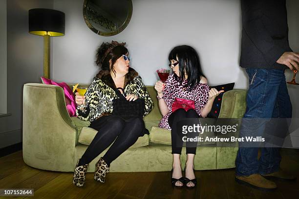 females on a sofa at a party fancy a male guest - bizarre fashion 個照片及圖片檔