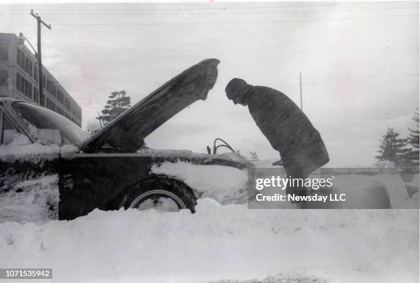 Day after abandoning his car in the snow, a man checks under the hood of the car on February 10, 1969 in Mineola, New York.